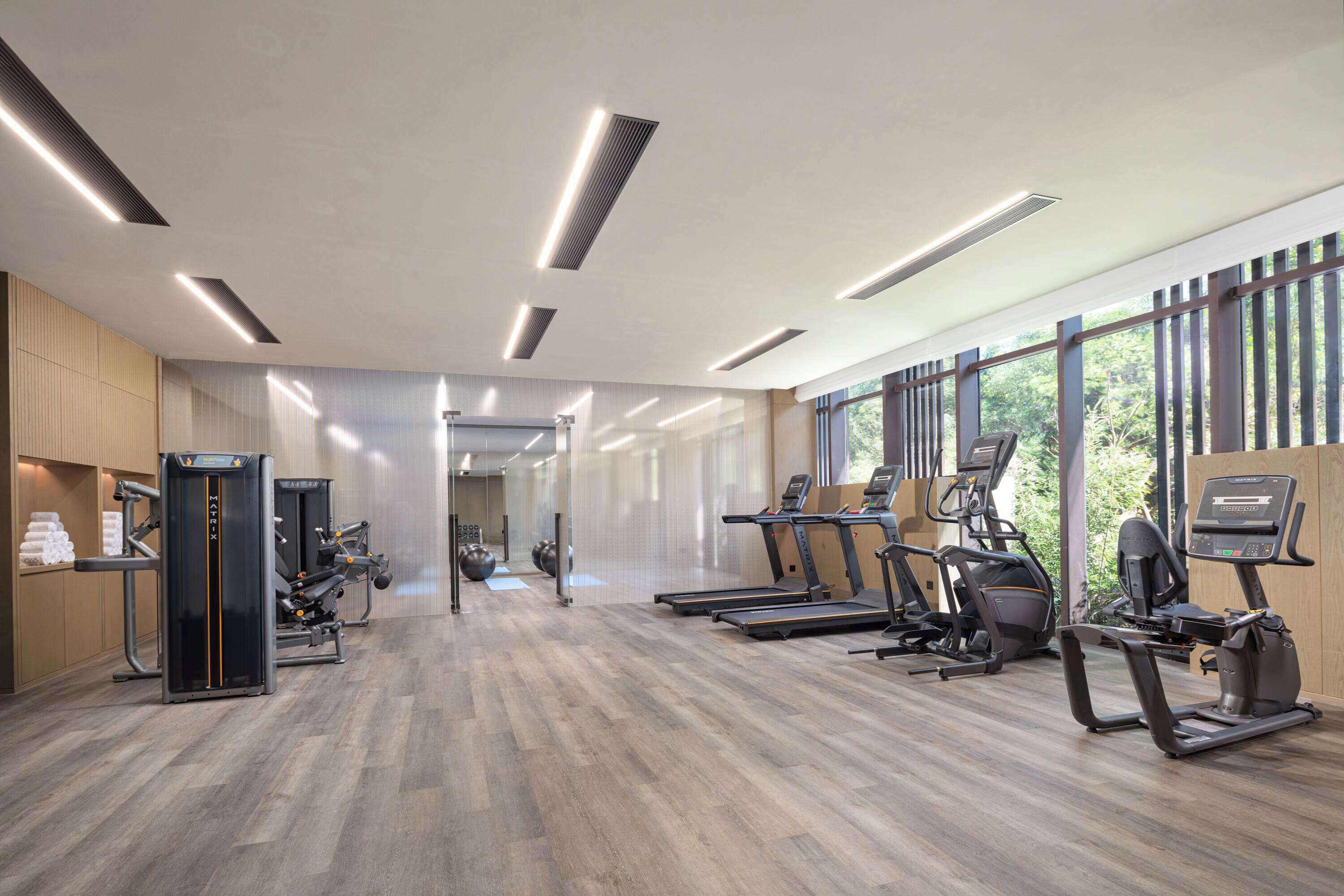 Un gimnasio moderno con cintas de correr, elípticas y equipo de pesas.