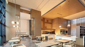A modern restaurant with multiple dining tables and chairs, a bar area, and a kitchen in the background. - Wyndham Fuzhou Guian (Fuzhou)