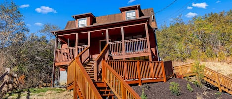 Step up to the entrance of this charming cabin, featuring a balcony and a beautifully landscaped garden.