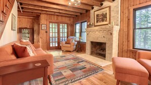 L’intérieur d’un chalet chaleureux, avec des murs en bois, une cheminée, un canapé et un tapis.