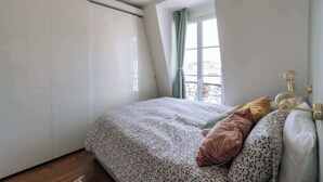 Une chambre à coucher avec un lit, des oreillers, une fenêtre et une armoire.