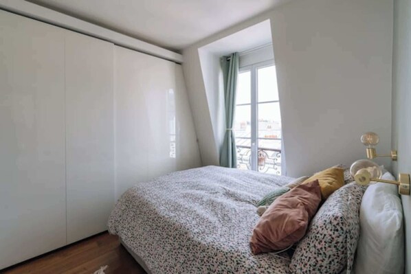 Un dormitorio con cama, almohadas, una ventana y un armario.