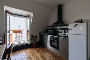 A compact kitchen with a large window, a built-in oven, and a refrigerator.