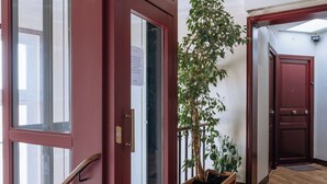 Ein Flur mit Holzboden, einer roten Tür mit Fensterteil und einem Blumentopf.