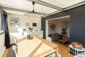 Ein zeitgemäßer Wohnbereich mit Esstisch aus Holz, weißen Sofas und einem grauen Sofa.