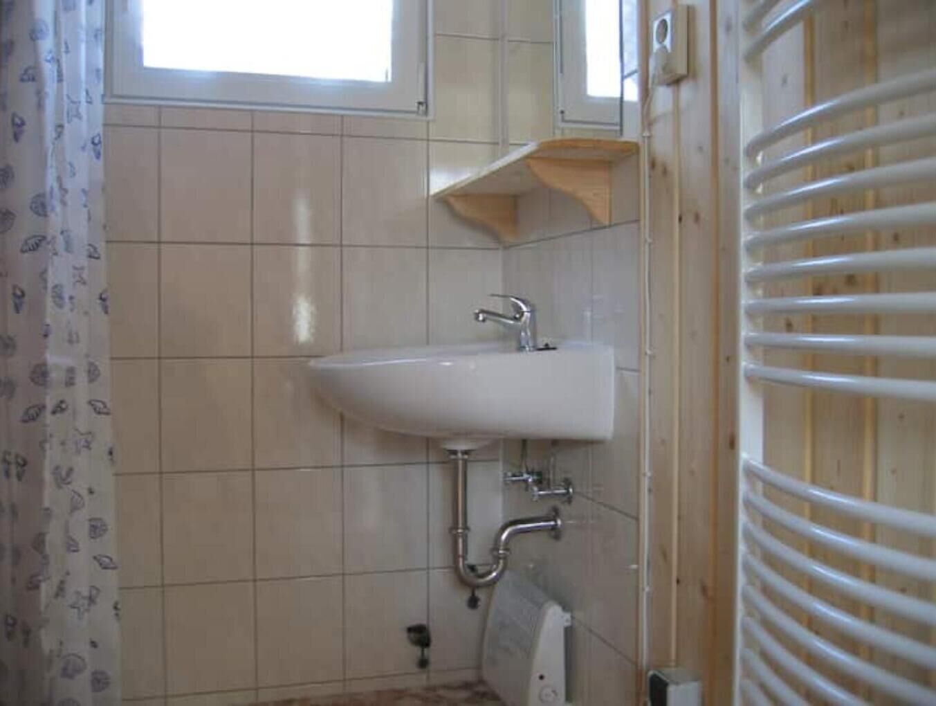 Een badkamer met een witte wastafel, een raam en een handdoekhouder.