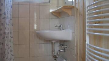 Une salle de bain avec un lavabo blanc, une fenêtre et un porte-serviettes.