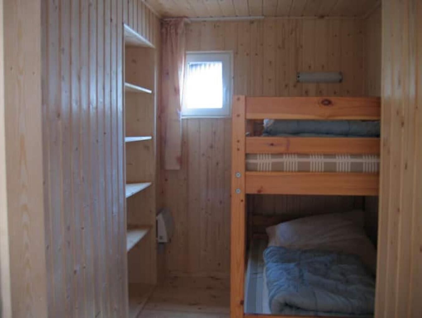 Ein kleiner, hölzerner Raum mit einem Etagenbett und einem Fenster.