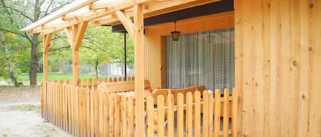 A wooden structure with a pergola and a fenced patio area.