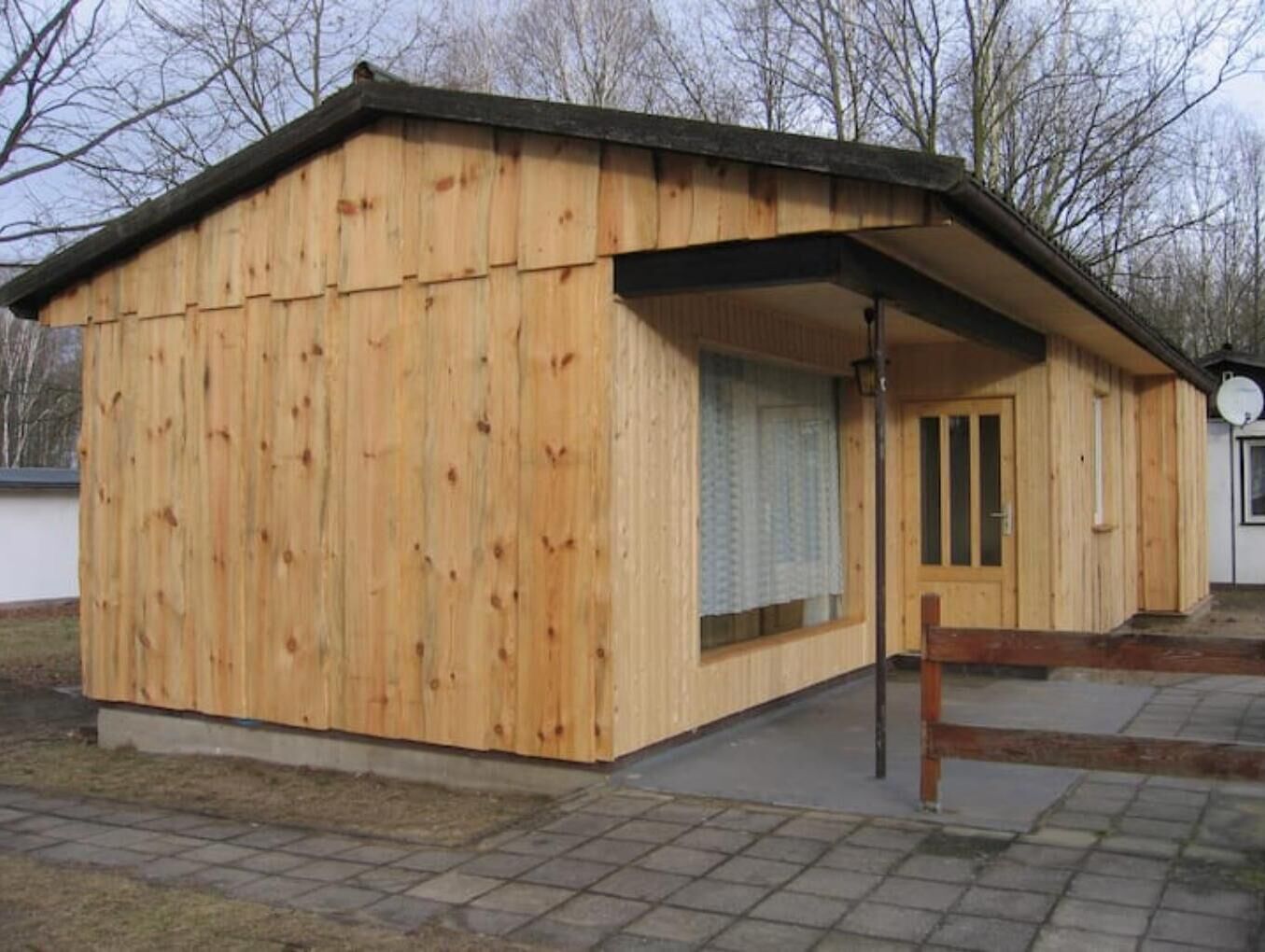 A wooden building with a sloped roof, a door, and a window.