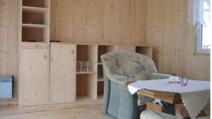 Une pièce aux murs en bois, avec un meuble intégré doté d’étagères, une chaise et une petite table recouverte d’une nappe blanche.