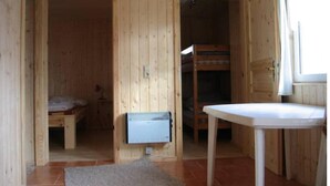 Une cabane en bois avec un lit superposé, une petite table et un radiateur.