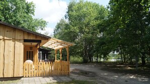Une cabane en bois dotée d’un porche couvert et d’une allée dallée.