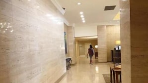 Un ampio corridoio con pavimenti e pareti in marmo lucidato, che conduce a una stanza con un letto e una scrivania.