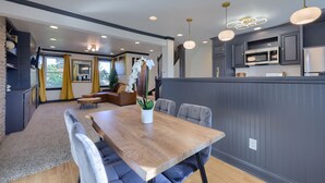 A modern kitchen with dark cabinetry, a wooden dining table, and pendant lighting. - Modern Downtown Lancaster Apt – Walk to Train & Amtrak (Lancaster)