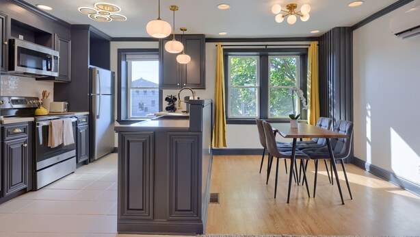 A modern kitchen with dark cabinetry, stainless steel appliances, and pendant lighting. - Modern Downtown Lancaster Apt – Walk to Train & Amtrak (Lancaster)