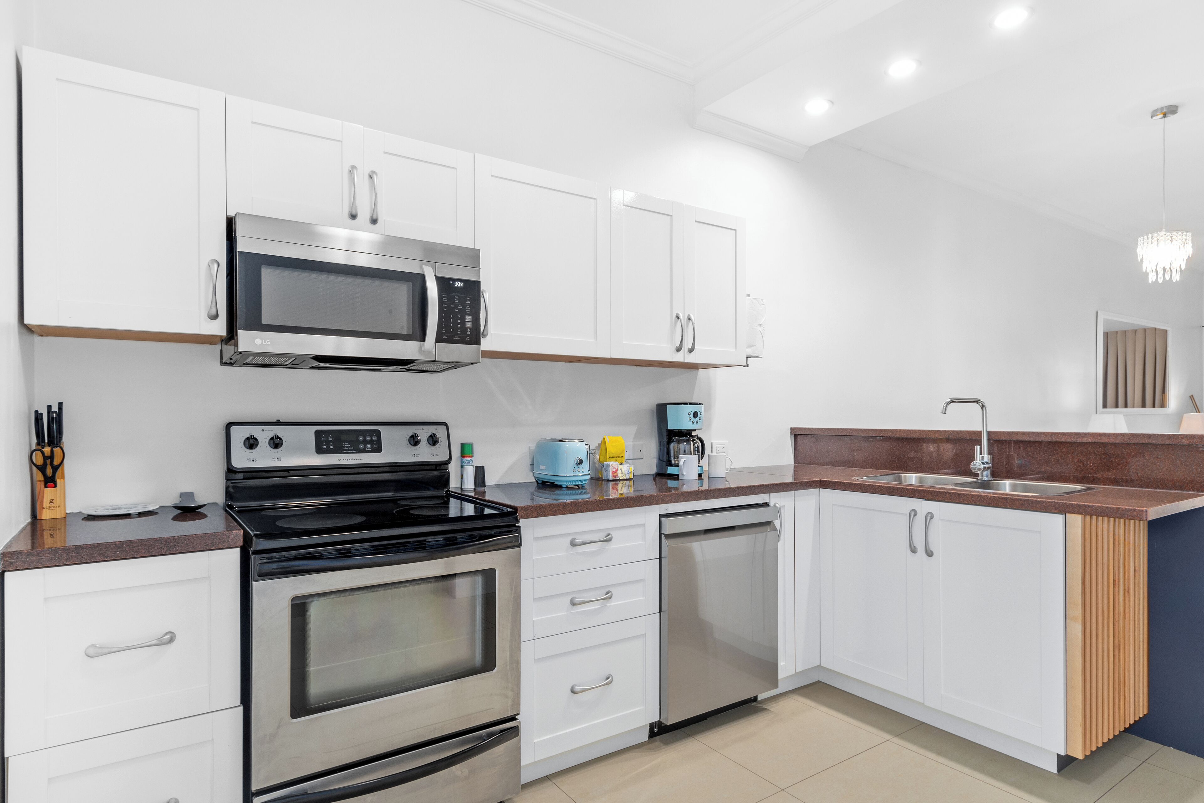 A modern kitchen with white cabinets, stainless steel appliances, a microwave, stove, and dishwasher.
