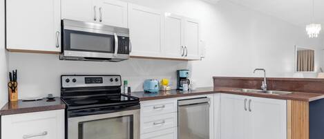 A modern kitchen with white cabinets, stainless steel appliances, a microwave, stove, and dishwasher.