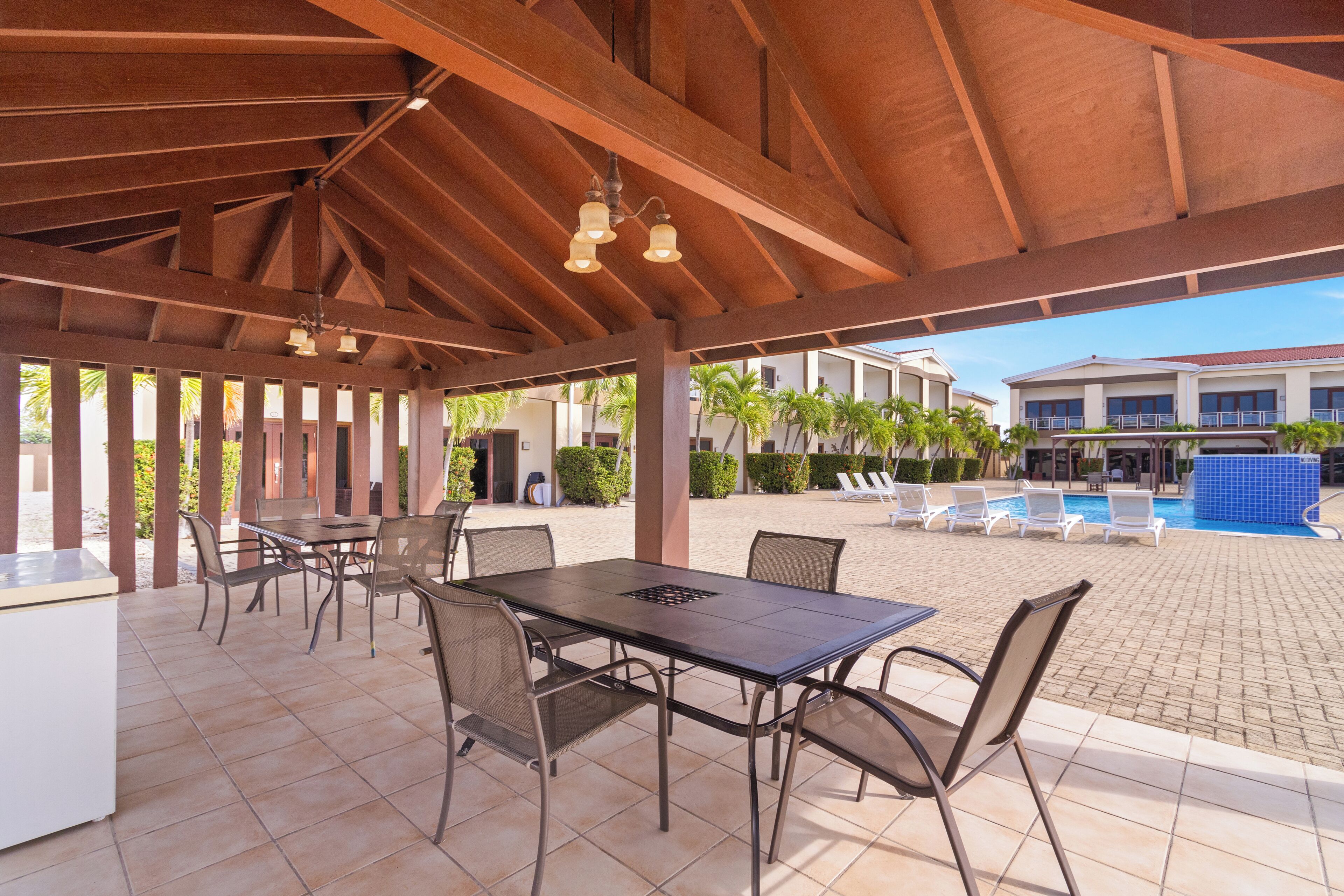 An outdoor patio with a covered dining area, pool, and poolside lounge chairs.