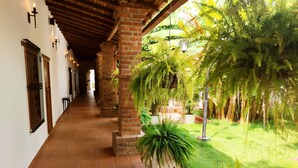 A corridor with brick columns, tiled flooring, and potted ferns.