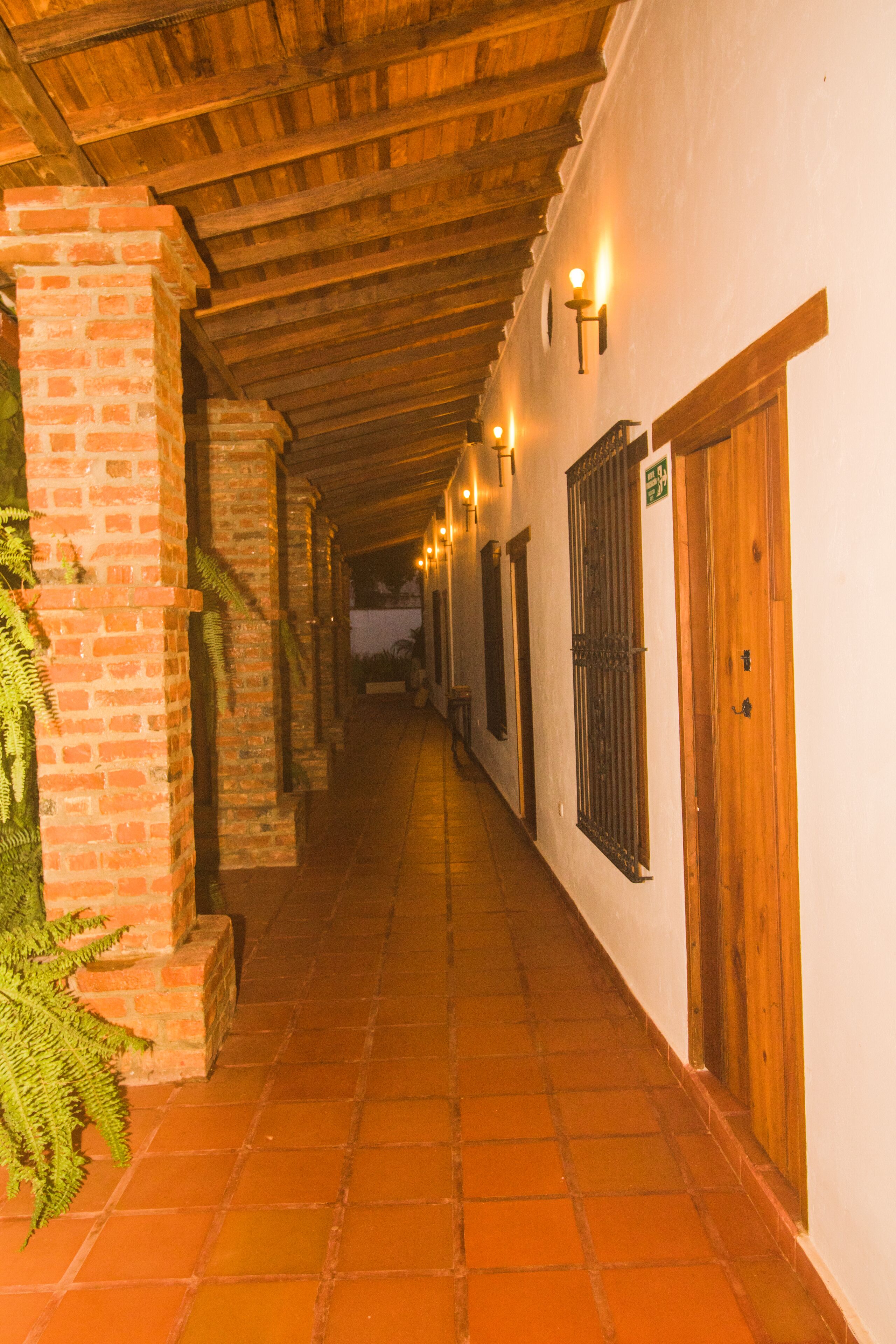 A corridor with brick walls, wooden doors, and tiled flooring.