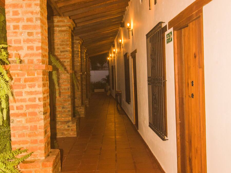 Un pasillo con paredes de ladrillo, puertas de madera y suelo de baldosas.