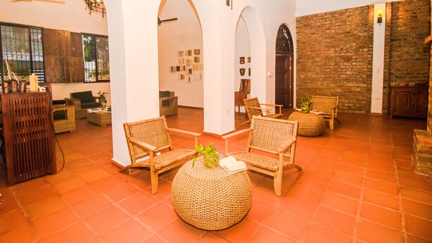 A spacious lobby with high ceilings, arched doorways, and a mix of wicker furniture and a large woven ottoman.