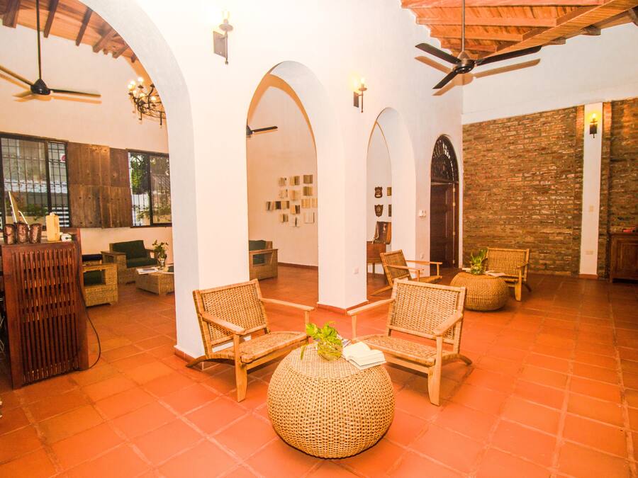 A spacious lobby with high ceilings, arched doorways, and a mix of wicker furniture and a large woven ottoman.