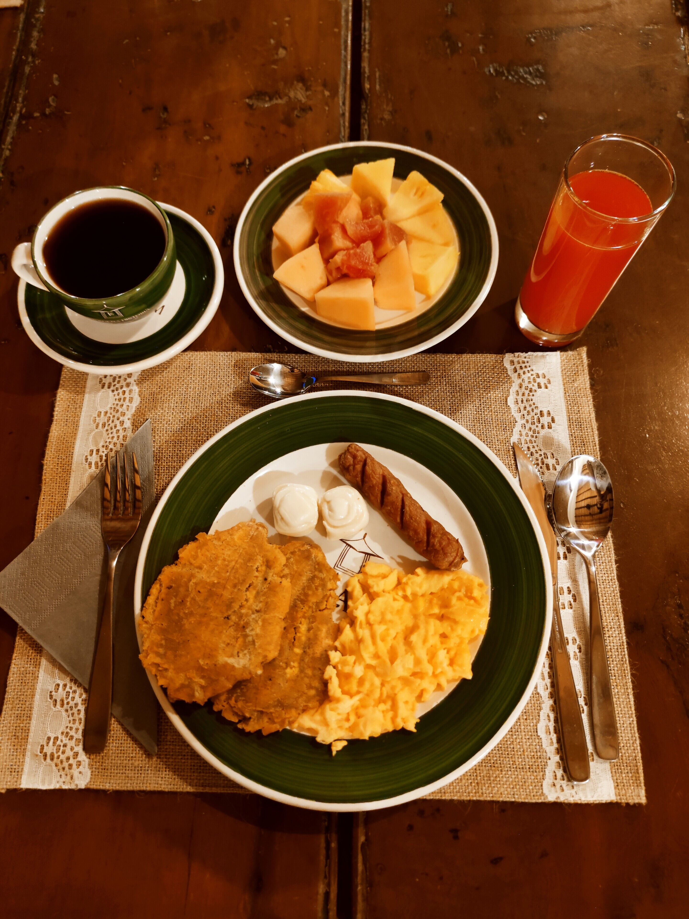 A table with a plate of food, a cup of coffee, and a glass of juice.
