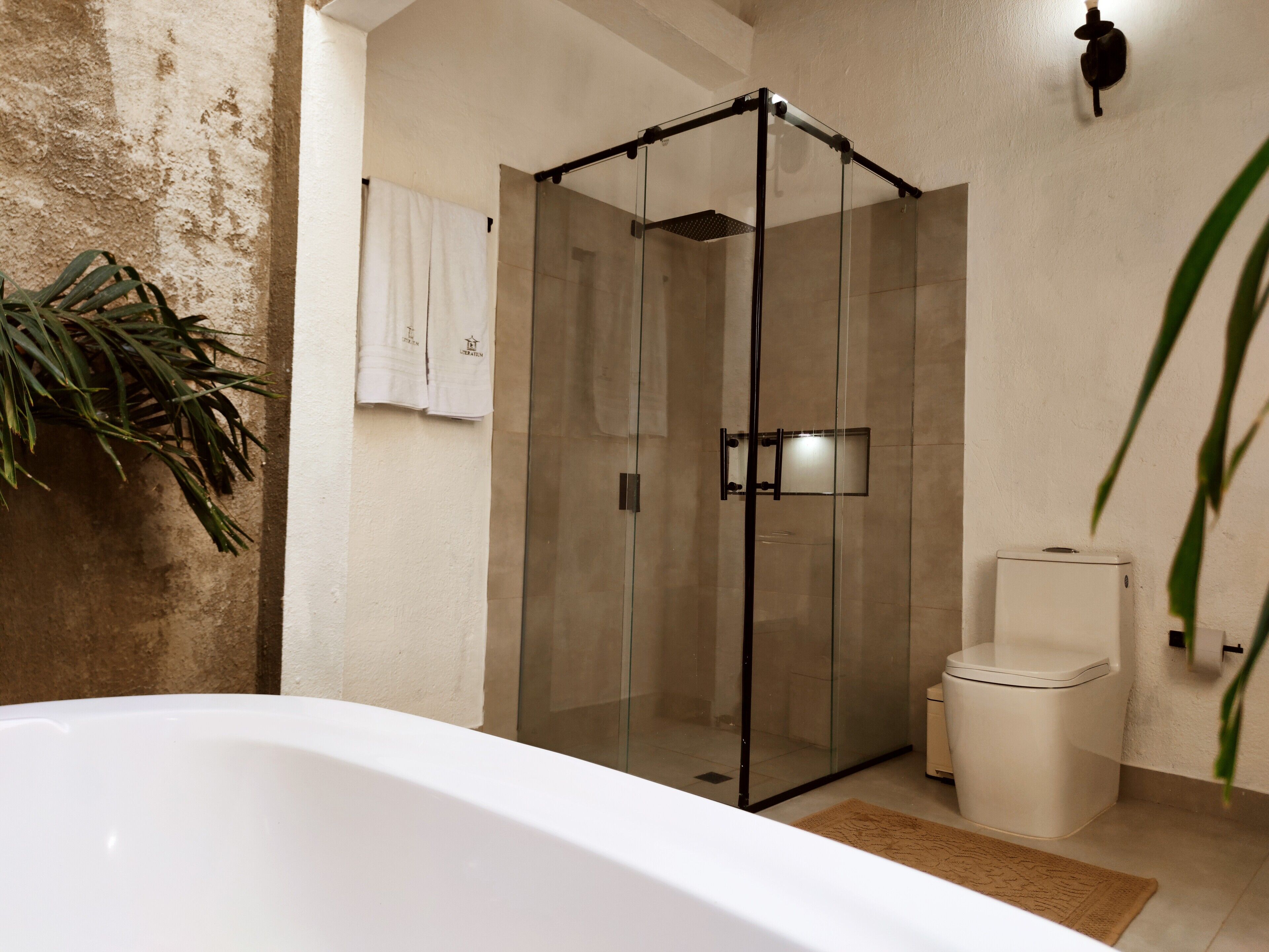 Un baño moderno con ducha envuelta en vidrio, inodoro blanco y bañera.