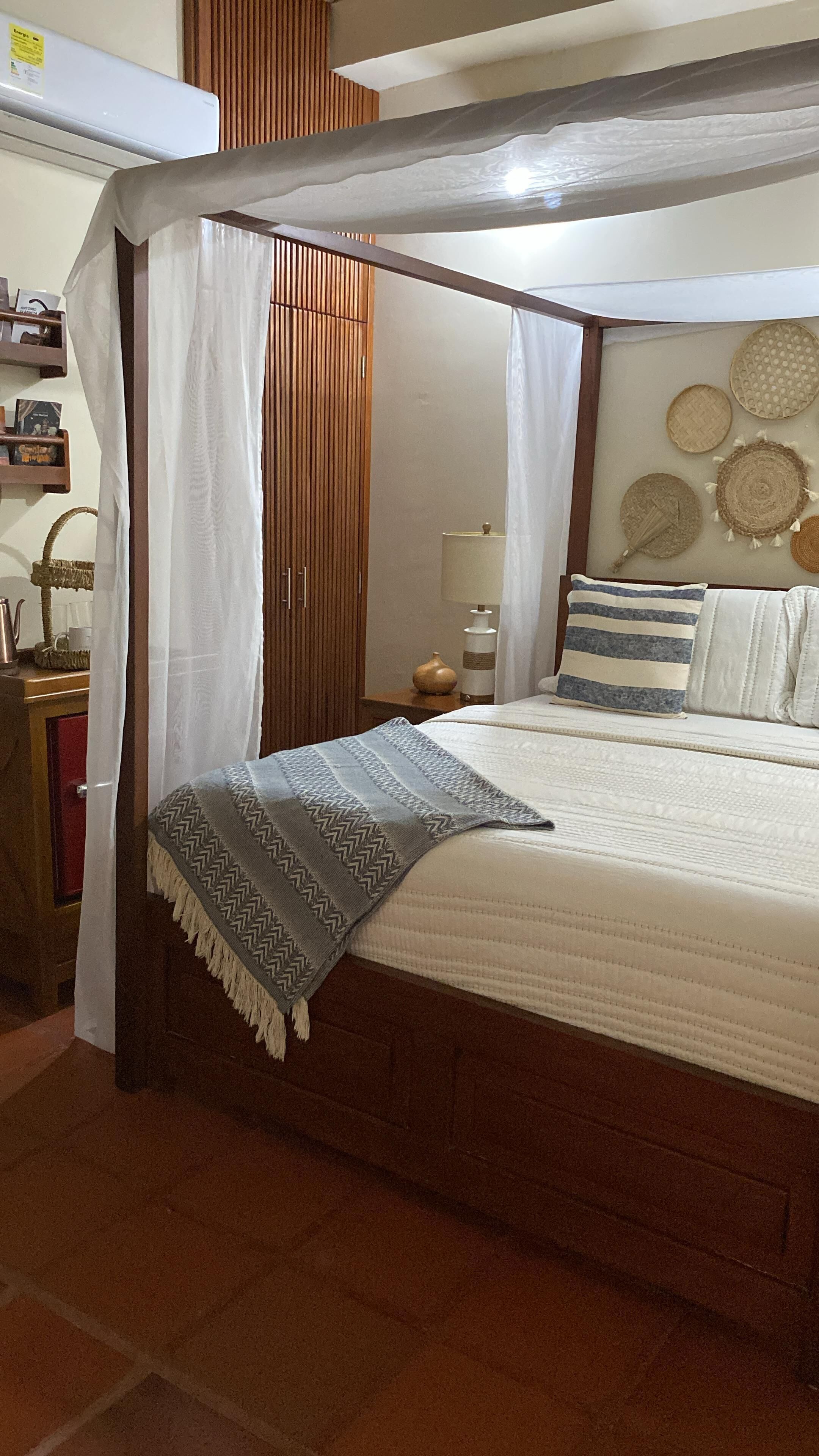 Une chambre à coucher avec un lit à baldaquin, une table de chevet avec une lampe et une étagère murale agrémentée d’objets décoratifs.