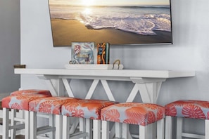 A white console table with a framed picture of a beach scene, two books, and a small decorative item. - Pet Friendly Beachfront with Heated Pool & Fire Pit (Crystal Beach)