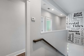A staircase with a handrail and a wall with a word cloud of travel-related words. - Pet Friendly Beachfront with Heated Pool & Fire Pit (Crystal Beach)