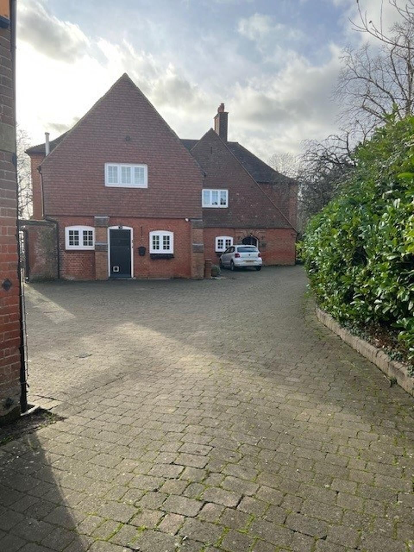 A two-story brick house with a paved driveway and a car parked in the front.