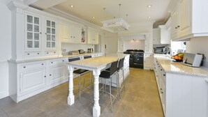 Una cocina amplia con armarios blancos, encimera de granito y una isla central con taburetes de bar.