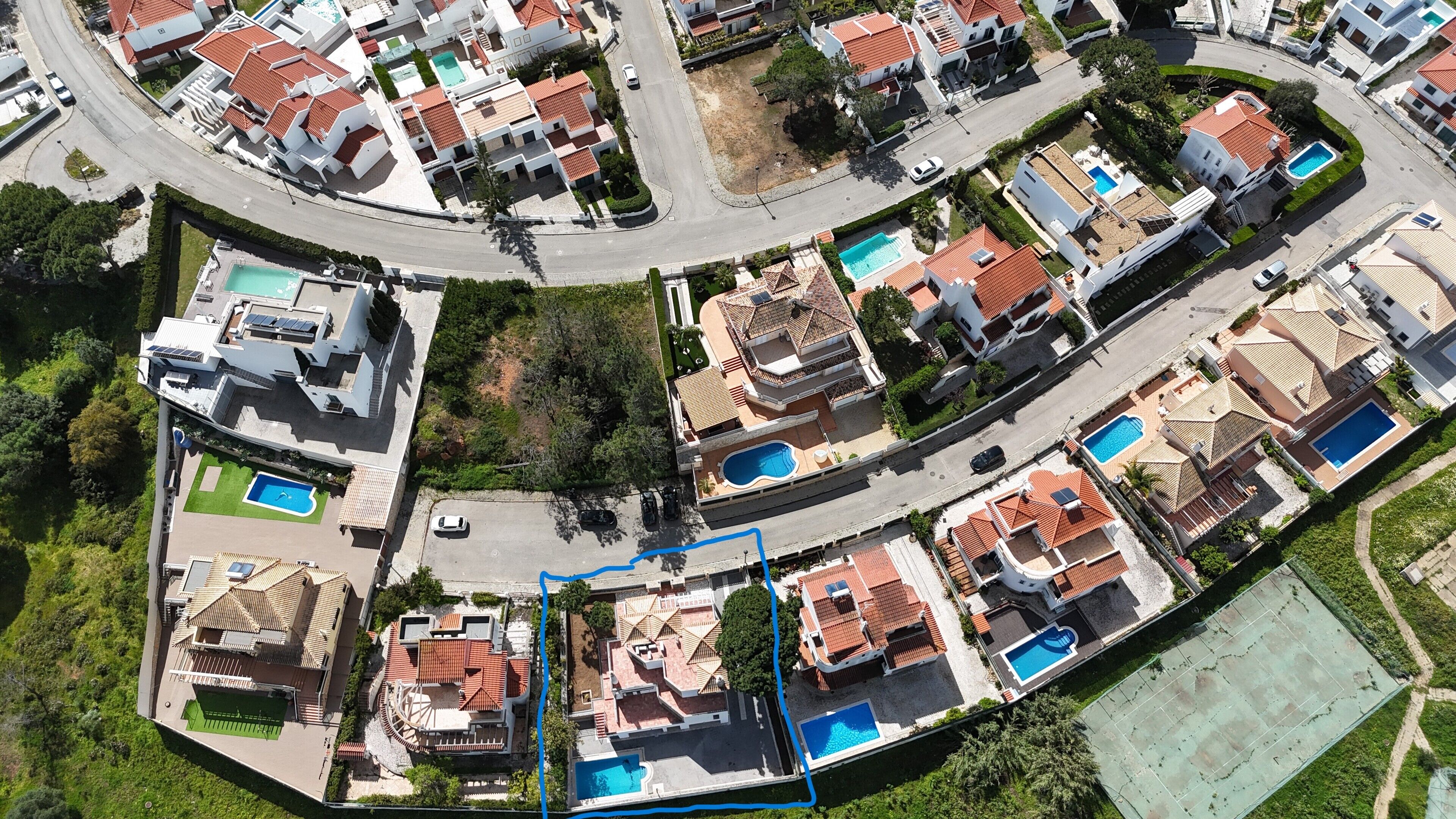 An aerial view of a residential area with houses, roads, and swimming pools.