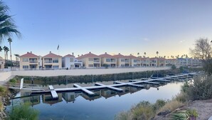 A marina with docked boats, a calm water body reflecting the buildings, and a row of multi-story residential buildings with balconies. - Snowbird Winter Villa (Bullhead City)