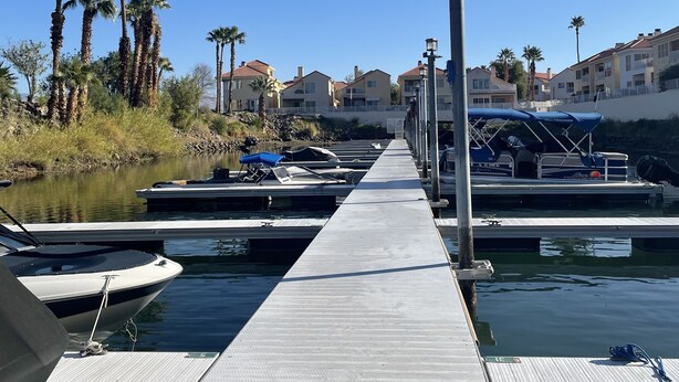 A marina with docked boats, a wooden walkway, and buildings in the background. - Snowbird Winter Villa (Bullhead City)
