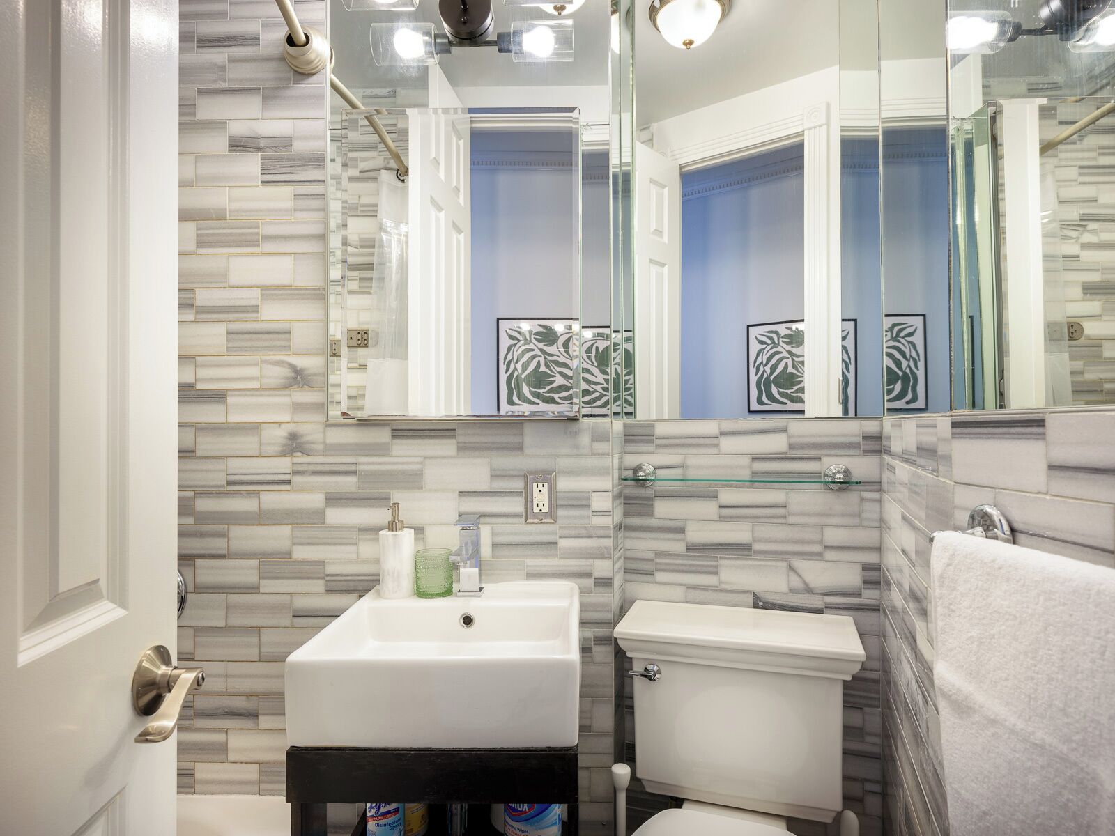 Une salle de bain avec un lavabo blanc, des toilettes et une étagère en verre.