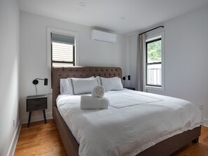 Un dormitorio con una cama grande, una mesita de noche y una ventana.