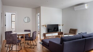 Una sala moderna con sofá, televisión y comedor.