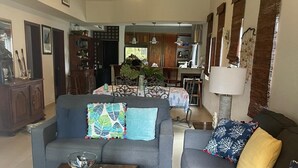 Ein geräumiges Wohnzimmer mit grauem Sofa, einem Couchtisch und einem Essbereich im Hintergrund.
