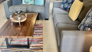 Ein Wohnzimmer mit grauem Sofa, einem Holztisch und einem farbenfrohen Teppich.