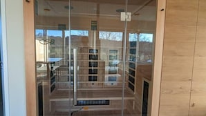Een moderne kamer met een glazen wand, houten vloer en zichtbaar ventilatiesysteem.