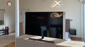 Een moderne woonkamer met een grote flatscreen-tv, minimalistische meubels en moderne verlichtingsarmaturen.