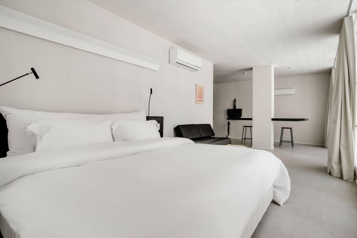 A modern hotel room with a large bed, a desk, and a chair.