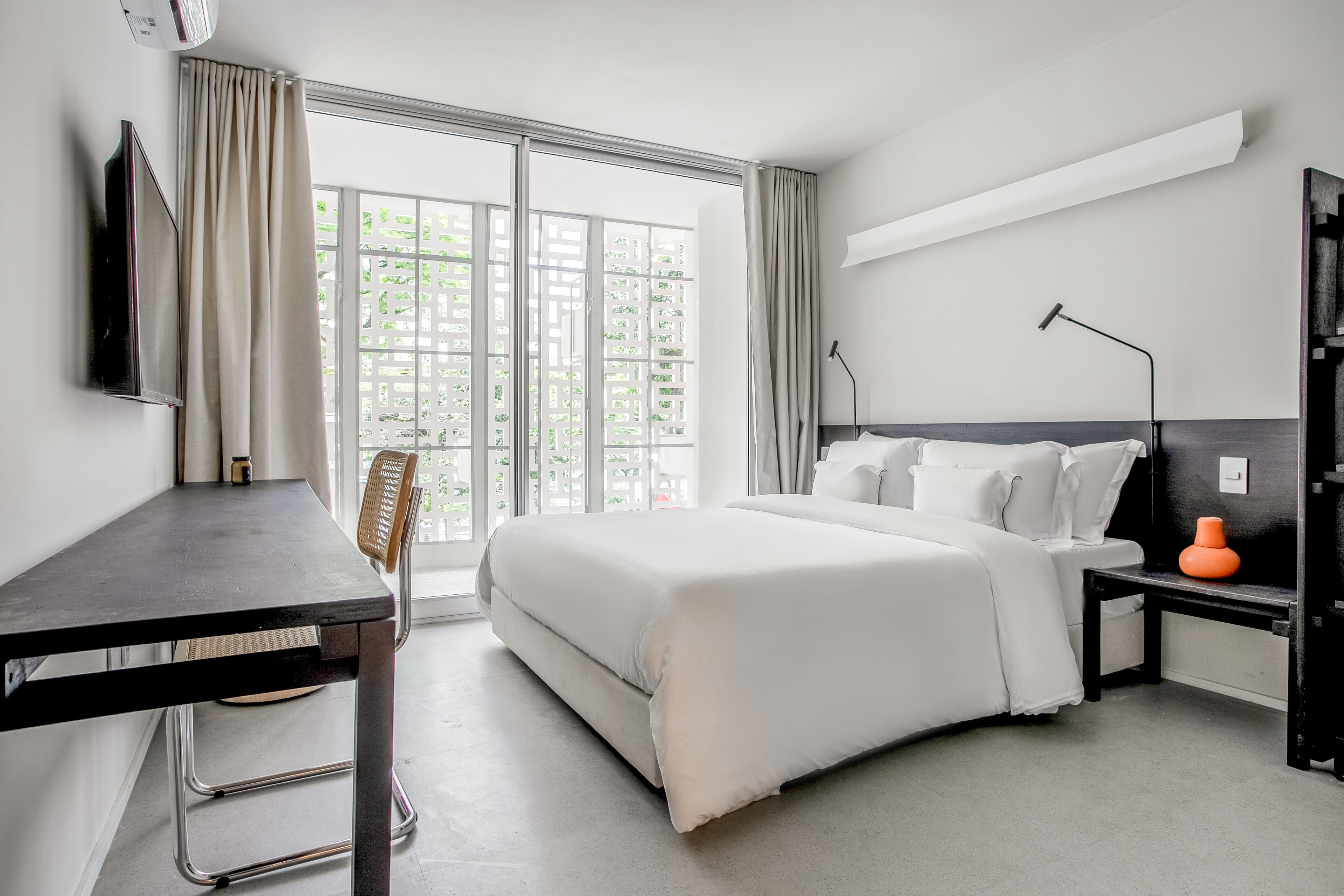 A modern hotel room with a large bed, a desk, and a chair.