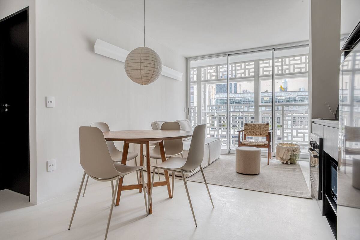 A modern kitchen with a dining area, large windows, and a view of the cityscape.