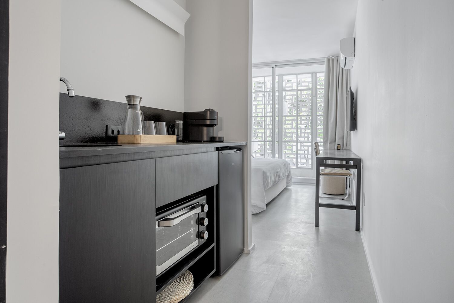 A modern kitchen with a built-in oven, a coffee maker, and a small dining area with a chair.