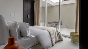 Quarto moderno com cama, janela e vista para a varanda externa.